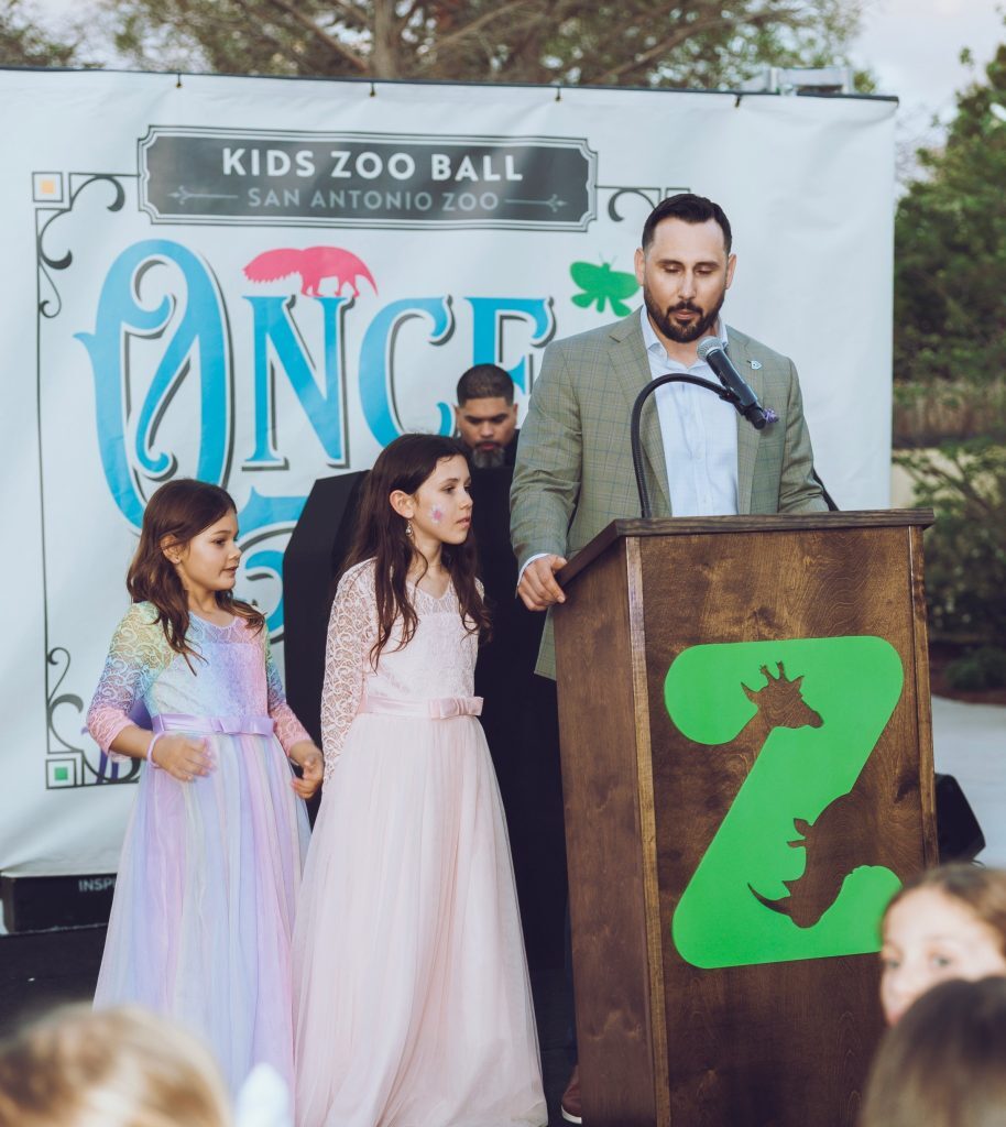 Robby Brown giving a speech at the San Antonio Zoo "Kids Zoo Ball" with his daughters standing alongside him at the podium